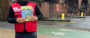 A Big Issue North vendor holding a magazine